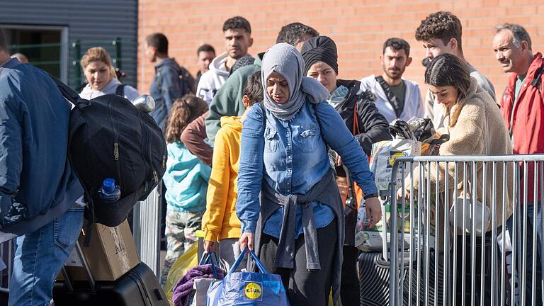 Flüchtlinge gehen in einer Erstaufnahmeeinrichtung zu einem wartenden Bus. - Flüchtlinge gehen in einer Erstaufnahmeeinrichtung zu einem wartenden Bus. Flüchtlinge gehen in einer Erstaufnahmeeinrichtung zu einem wartenden Bus. - Flüchtlinge gehen in einer Erstaufnahmeeinrichtung zu einem wartenden Bus.