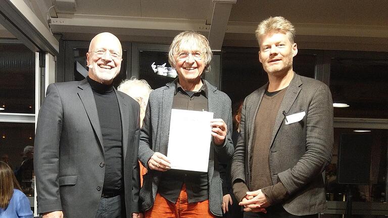 In Berlin nahm Norbert Dietzel (Sprecher Verein Aktion Eine Welt Bad Neustadt, Mitte) von Christian Felber (Gründer der Gemeinwohlökonomie, rechts) und Moderator Michael Stober (links) die Zertifizierung entgegen.