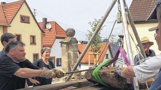 Aus dem dunklen Schacht ans Tageslicht befördert: Ein rund 250 Kilogramm schweres Steinfragment, vielleicht Teil einer Grabplatte. Vorne links Grabungsleiter Bernhard Häck mit der Brechstange bei der Bergung.FOTO: Sabine Wagner