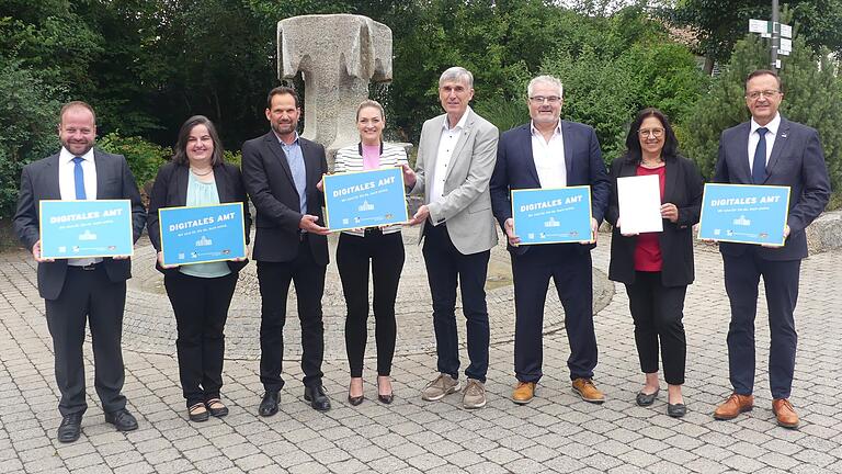 Vorbildliches 'Clickbaiting' in den Rathäusern: Bürgermeister Steffen Malzer (Ostheim), Bürgermeisterin Sonja Reubelt (Sandberg), Thomas Nixel, IT-Projektmanager des Landratsamts, Digitalministerin Judith Gerlach, stellvertretender Landrat Thomas Vizl, Bürgermeister Willi Warmuth, Ayfer Rethschulte, Dritte Bürgermeisterin der Stadt Schweinfurt sowie Bürgermeister Ludwig Nätscher (Poppenhausen) mit den Digital-Plaketten.