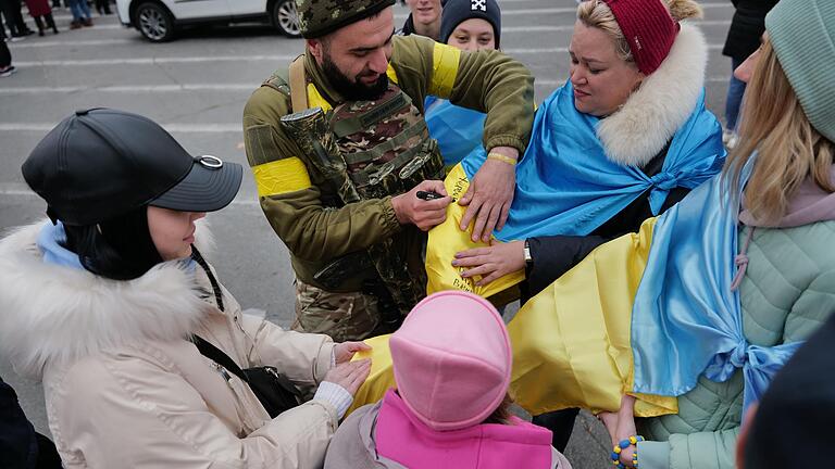 In Cherson sind Autogramme ukrainischer Soldaten auf ukrainischen Fahnen sehr gefragt. In Cherson sind Autogramme ukrainischer Soldaten auf ukrainischen Fahnen sehr gefragt.