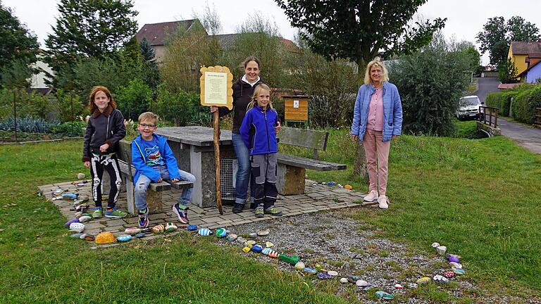 Initiatorin Manuela Michalzik und Bürgermeisterin Martina Rottmann (rechts) bei der Steinschlange am Oberpleichfelder Ortsrand. Die bunt bemalten Steine ziehen nun um in den Eingangsbereich des Kindergartens.