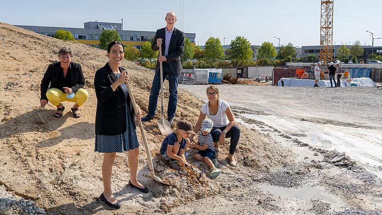 Die zwei Nachwuchskräfte Albert und Vincent Lang inspizieren gemeinsam mit ihrer Mutter Marieluise Lang (rechts) und SKZ-Geschäftsführer Thomas Hochrein (Mitte) sowie Sozialreferentin Hülya Düber (2. von links) und stellvertretender Leiterin des Fachbereichs Jugend und Familie Monika Kraft (links) - beide von der Stadt Würzburg - die Baustelle für die neue Kita des SKZ am Friedrich-Bergius-Ring.