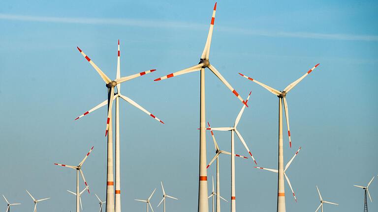 Windräder stehen auf den Hügeln zwischen Äckern (Symbolbild). Das Überlandwerk Rhön will künftig mehr ökologischen Strom selbst produzieren.