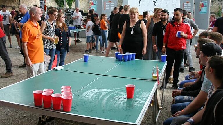 Dieses Symbolbild von einer Veranstaltung im Landkreis Würzburg im Jahr 2018 veranschaulicht das Prinzip, nach dem eine Beerpong-Partie abläuft. Mitglieder zweier Teams versuchen Tischtennisbälle in die Becher des gegnerischen Teams zu werfen. Die Gegner müssen diese dann austrinken.