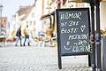 Ein Aufsteller mit der Aufschrift 'Humor ist die beste Medizin... und Kuchen' steht vor einer Bäckerei in der Hauptstraße in Haßfurt. Humor brauchen in Zeiten von Corona auch Existenzgründer. Die Stadt hat deshalb für Gründer ein eigenes Förderprogramm aufgelegt.