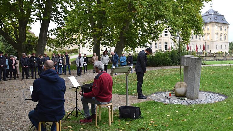 Am Mahnmal im Schlosspark Werneck legten bei der Gedenkfeier für die Opfer der Heil- und Pflegeanstalt am 3. Okober einige Besucher weiße Rosen nieder, hier Bürgermeister Sebastian Hauck, Hauptredner des Gedenkens.