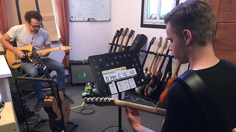 Gitarrenlehrer Gerald Brand (links) setzt im Unterricht die Akkord-Spielkarten ein, die seinem Schüler vorgeben, was er spielen soll. Gitarrenlehrer Gerald Brand (links) setzt im Unterricht die Akkord-Spielkarten ein, die seinem Schüler vorgeben, was er spielen soll.