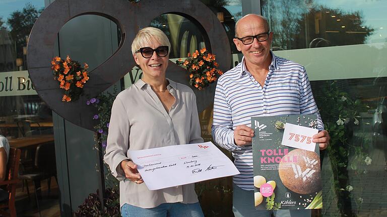 LGS-Geschäftsführerin Claudia Knoll und Ernst Köhler, Inhaber der Köhlers Vollkornbäckerei, bei der Scheckübergabe vor der 'Blumenbrezel' der jüngsten Köhlers-Filiale am Hubland.