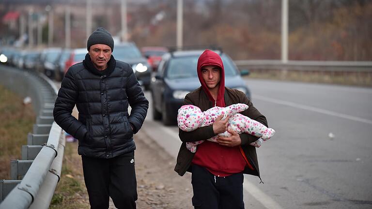 Zwei Männer mit einem Kind gehen in Richtung der polnischen Grenze. Trotz der internationalen Appelle für ein Ende des Kriegs hat Russland seine Angriffe auf die Ukraine verschärft.