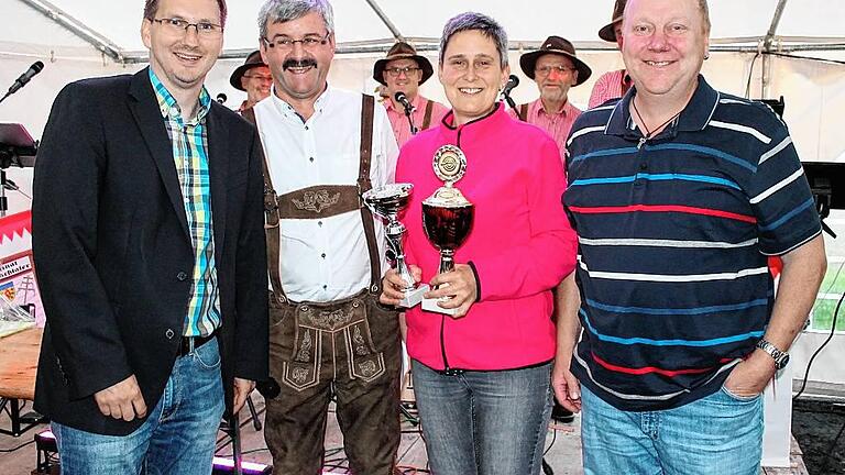 Bürgermeister Wolfram Thein und Sportleiter Erich Schwab gratulieren der erfolgreichen Schützin Beatrice Hofmann zum Pokal in der Disziplin &bdquo;Glück&ldquo; und zu dem Wanderpokal, eine großzügige Spende von Uli Hellmuth (von links nach rechts). Auch die &bdquo;Original Preppachtaler&ldquo; im Hintergrund freuen sich mit der Gewinnerin.