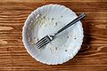 Empty plate of food after meal on a wooden table       -  _