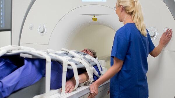 Eine medizinisch-technische Radiologieassistentin bereitet einen Mann für eine Kernspintomografie vor. Eine medizinisch-technische Radiologieassistentin bereitet einen Mann für eine Kernspintomografie vor.