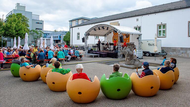 Vor der Sommerbühne hat es sich das Publikum an Biertischgarnituren und extravaganten Sesseln bequem gemacht.