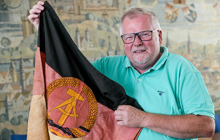 Eberhard Schellenberger mit der DDR-Fahne, die ihm Bernd Höland, der Gründer des Freundeskreises Suhl in Würzburg, kürzlich geschenkt hat. Die Flagge hing einst an der innerdeutschen Grenze.