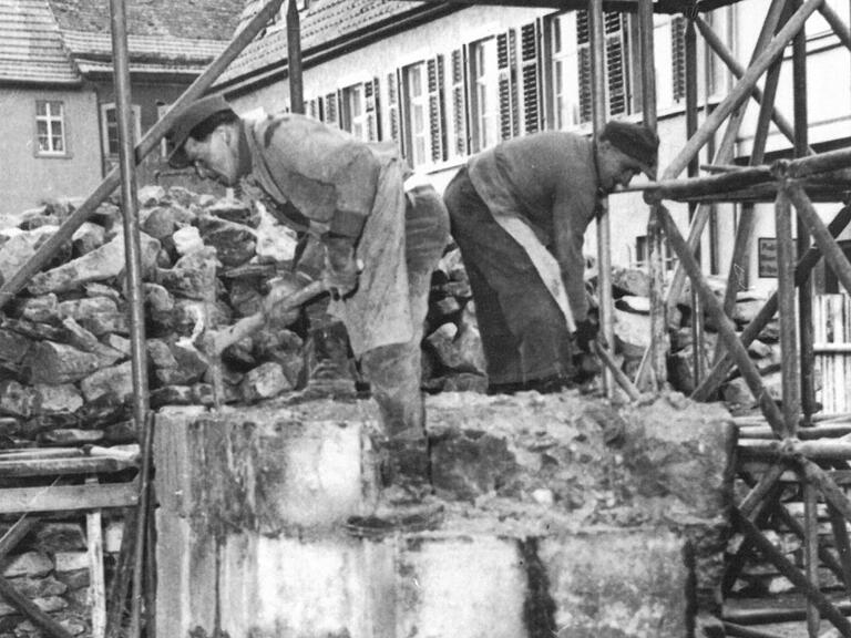 Zwei Männer bearbeiten mit der Hacke den rechten Pfeiler des Kirchturms. Zwei Männer bearbeiten mit der Hacke den rechten Pfeiler des Kirchturms. 