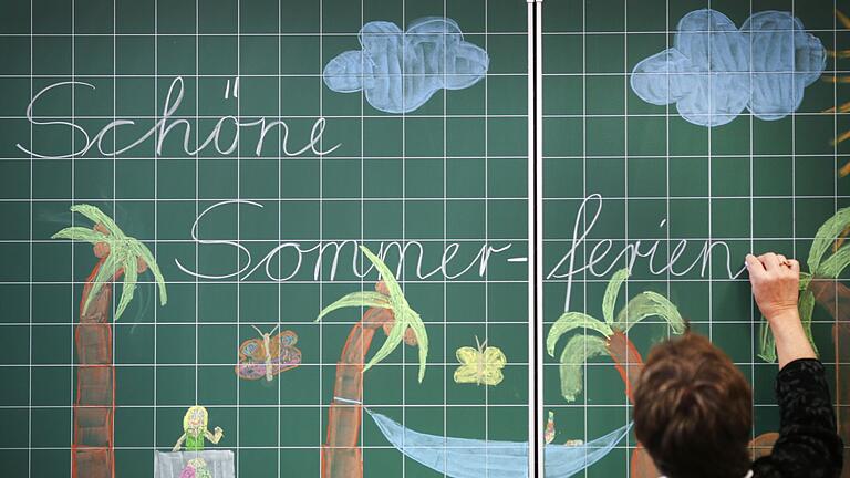 Sommerferien - Eine Lehrerin schreibt „Schöne Sommerferien” an die Tafel einer Grundschulklasse. (Archivfoto) Sommerferien - Eine Lehrerin schreibt „Schöne Sommerferien” an die Tafel einer Grundschulklasse. (Archivfoto)