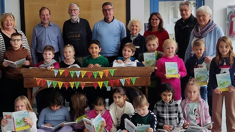 Spendenübergabe an der Siedlungsgrundschule am bundesweiten Vorlesetag: Klasse 2e und hinten von rechts nach links: Elisabeth Ackermann (SieNet), Lesepate Konstantin Wehr (Lesepate) , Sabine Hipskind (Lesebeauftragte), Sibylle Heisel (Schriftführerin SieNet), Ralf Machwart (Vorsitzender Siedlervereinigung), Jürgen Thorand (Lesepate), Martin Tröge (Kassier SieNet), Heike Schneller-Schneider (Rektorin Grundschule Kitzingen-Siedlung).