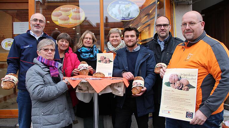 In der Winterhäuser Bäckerei Fuchs wird ein Walnussbrot angeboten. Die Nüsse werden von den Walnussknackern angeliefert (von links): Georg Bischof (Referent für Hospizarbeit, Malteser), Gabriele Schmoll, Christine Hidringer, Maria Maak (alle Walnussknacker), Petra Endres (Bäckerei Fuchs), Bastian Lange (ILE Maindreieck), Bürgermeister Christian Luksch, Bäcker Andreas Rother.