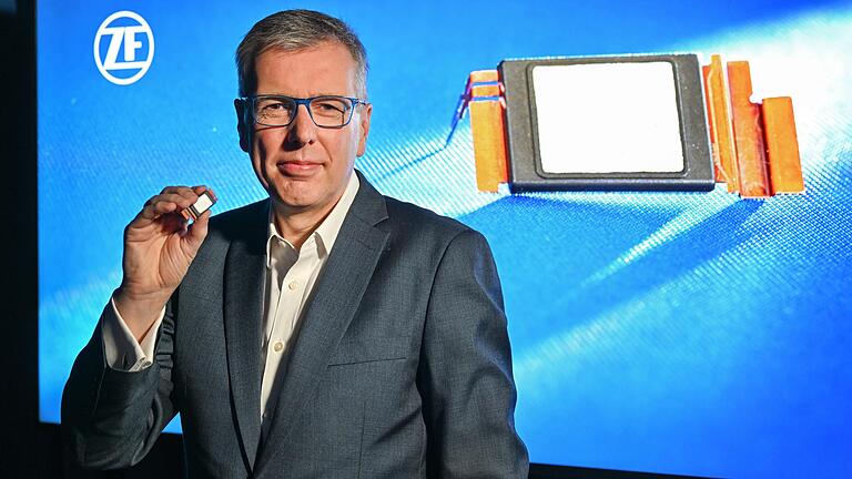 Holger Klein, Vorstandsvorsitzender (CEO) des ZF-Konzerns, zeigt vor einem Bildschirm ein Modul mit Siliziumkarbid-Chips, das im Inverter den Gleichstrom in Wechselstrom wandelt. Klein stellte am Donnerstag die Geschäftszahlen für 2022 vor und stellte dabei Mobilitätswende in den Mittelpunkt.