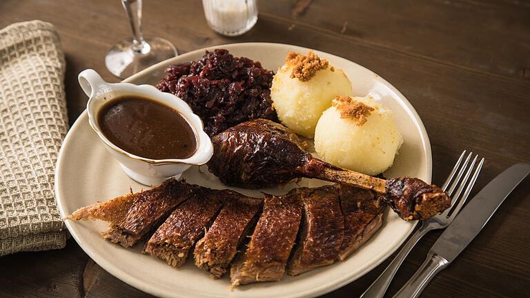 Gans wird mit Rotkohl, Klößen und Sauce serviert       -  Eine schwere Bratensoße zur Gans? Mit Hilfe von Küchenkrepp lässt sie sich leicht etwas entfetten.