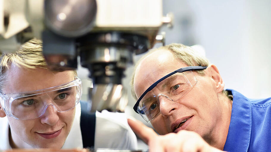 closeup picture: trainer and apprentice in vocational training on a milling machine - teacher explains details of the machine       -  In unterschiedlichsten Branchen - vom Handwerk über Dienstleistung bis hin zu Medizin und Pflege - finden sich Angebote auf dem Karriereportal der Region, jobs.mainpost.de.