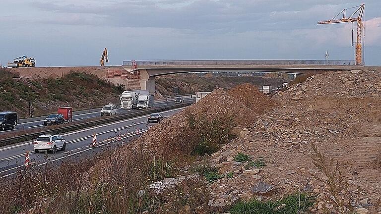 Etwa acht Meter geht es von der neuen Brücke über der A3 zwischen Albertshofen und Mainsondheim bis zur Autobahnfahrbahn runter. Dieser Abstand wird sich noch verringern, denn nach dem sechsstreifigen Ausbau wird die Autobahn drei Meter höher verlaufen als jetzt. Allerdings ist die Brücke trotzdem höher als das Vorgängermodell, denn sie hat keinen Mittelträger, sondern wölbt sich in der Mitte nach oben – und auch am Rand müssen Schwer- und Sondertransporte passieren können. Fotos: Daniela Röllinger Etwa acht Meter geht es von der neuen Brücke über der A3 zwischen Albertshofen und Mainsondheim bis zur Autobahnfahrbahn runter. Dieser Abstand wird sich noch verringern, denn nach dem sechsstreifigen Ausbau wird die Autobahn drei Meter höher verlaufen als jetzt. Allerdings ist die Brücke trotzdem höher als das Vorgängermodell, denn sie hat keinen Mittelträger, sondern wölbt sich in der Mitte nach oben – und auch am Rand müssen Schwer- und Sondertransporte passieren können. Fotos: Daniela Röllinger