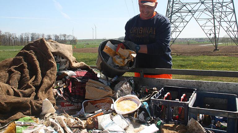 Tobias Hemmerich kippt einen Eimer mit dem im Straßengraben gesammelten Müll auf einen Pritschenwagen. Dort liegt bereits eine Menge der Hinterlassenschaften, die Verkehrsteilnehmer einfach so aus dem Fenster geworfen haben.