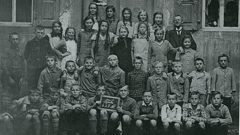 Klassenfoto des 6. und 7. Jahrgangs der Volksschule Kleinlangheim, entstanden 1935/36. Auf dem Bild ganz links unter dem Fenster Leo Ackermann. In dieser Aufnahme drückt sich seine doppelte Außenseiterstellung&nbsp; als Jude und als außereheliches Kind augenfällig aus.