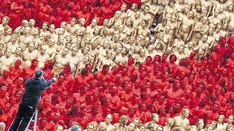 Rot und Gold auf nackter Haut: Vor der Bayerischen Staatsoper in München dirigiert der Installationskünstler Spencer Tunick 1700 Menschen per Megaphon. Das Happening steht im Zusammenhang mit der Münchner Ring-Inszenierung, mit der die Staatsoper ihre Festspiele startet.