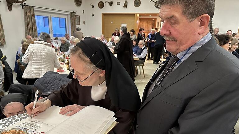 Schwester Ancilla trug sich als erste in das Goldene Buch der Gemeinde Rödelmaier ein. Darum hatte Bürgermeister Michael Pöhnlein (rechts) gebeten.