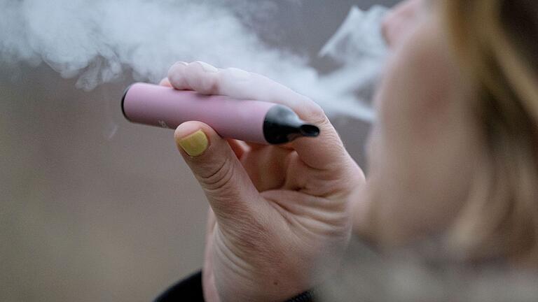 Eine Person raucht Einweg-Vape.jpeg - Die richtige Entsorgung von E-Zigaretten und ihren Komponenten ist wichtig, um Umweltverschmutzung zu verhindern. Eine Person raucht Einweg-Vape.jpeg - Die richtige Entsorgung von E-Zigaretten und ihren Komponenten ist wichtig, um Umweltverschmutzung zu verhindern.