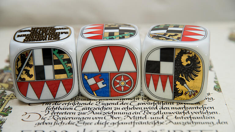 Frankenwürfel       -  Drei Frankenwürfel aus Porzellan zeigen die Seite der Auszeichnung mit den Wappen der Regierungsbezirke von Oberfranken (l-r), Unterfranken und Mittelfranken.