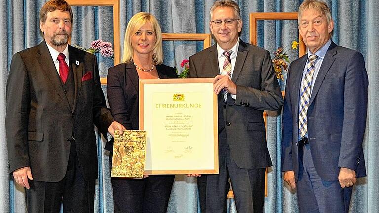 Helmut Dietz von der VG Mellrichstadt nimmt aus den Händen von Staatsministerin Ulrike Scharf die Urkunde für den schönsten Friedhof im Landkreis Rhön-Grabfeld entgegen. Der Präsident des Bayerischen Landesverbands für Gartenbau und Landespflege, Wolfram Vaitl (links), hält die Bronzeplakette, die ebenfalls verliehen wurde. Rechts: Dr. Otto Hünnerkopf, der Bezirks-Vorsitzende des Landesverbands für Gartenbau und Landespflege und Vizevorsitzender des Verbands auf gesamtbayerischer Ebene. Helmut Dietz von der VG Mellrichstadt nimmt aus den Händen von Staatsministerin Ulrike Scharf die Urkunde für den schönsten Friedhof im Landkreis Rhön-Grabfeld entgegen. Der Präsident des Bayerischen Landesverbands für Gartenbau und Landespflege, Wolfram Vaitl (links), hält die Bronzeplakette, die ebenfalls verliehen wurde. Rechts: Dr. Otto Hünnerkopf, der Bezirks-Vorsitzende des Landesverbands für Gartenbau und Landespflege und Vizevorsitzender des Verbands auf gesamtbayerischer Ebene.
