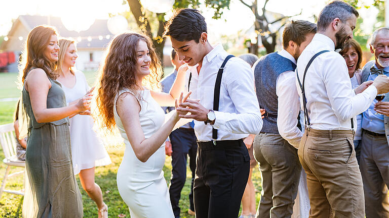 Guests dancing at wedding reception outside in the backyard.       -  So kommt keine schlechte Stimmung auf: Unterhalten Sie Ihre Gäste während des Shootings mit geplanten Programmpunkten.