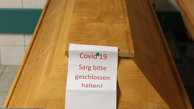 'COVID 19 Sarg bitte geschlossen halten' steht auf diesem Sarg. Das Gesundheitsamt Haßberge meldet im Landkreis vier weitere Todesfälle mit Corona. 'COVID 19 Sarg bitte geschlossen halten' steht auf diesem Sarg. Das Gesundheitsamt Haßberge meldet im Landkreis vier weitere Todesfälle mit Corona.