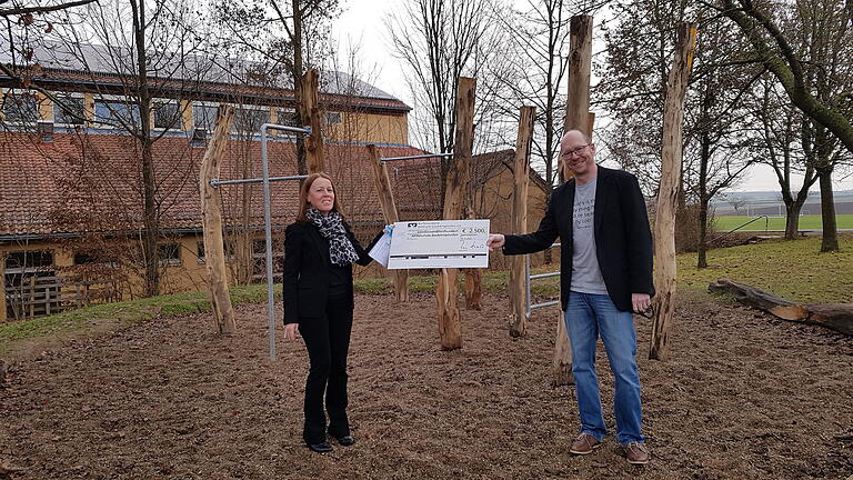 Bei der Spendenübergabe vor der Calisthenics-Anlage: Rektor Michael Hümmer und Heike Schüttenhelm, Prokuristin der Raiffeisenbank Bütthard-Gaukönigshofen.