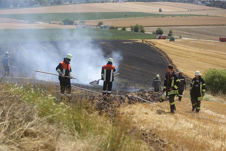 Für einen Flächenbrand auf dem abgeernteten Feld wird nicht viel Löschwasser gebraucht. Die Glutnester werden gezielt mit Feuerpatschen bearbeitet. Das Foto entstand in der Nähe von Bad Königshofen. (Archivbild)