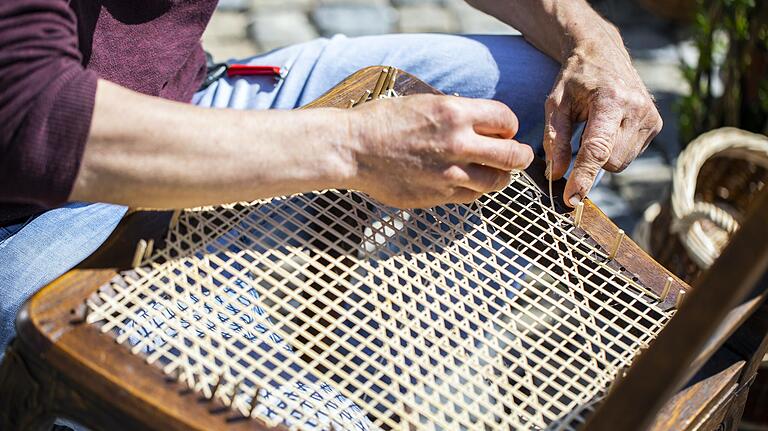 Stefan Rippstein erneuert mit Rattan-Schalen den Sitz eines alten Holzstuhls.