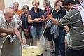 Pater Raja schwingt den großen Kochlöffel am Aschacher Dorfplatz. Er kochte in einem eigens aus Indien mitgebrachten Topf ein Gericht.  Foto: Sigrid Klemke       -  Pater Raja schwingt den großen Kochlöffel am Aschacher Dorfplatz. Er kochte in einem eigens aus Indien mitgebrachten Topf ein Gericht.  Foto: Sigrid Klemke