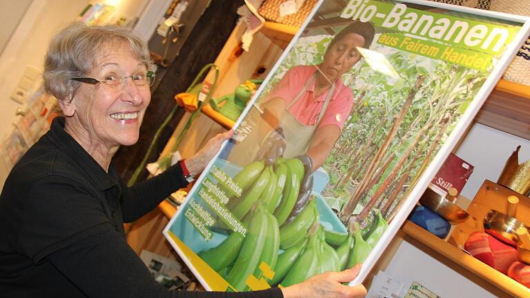 Christa Heinrich hängt im Kitzinger Weltladen ein Plakat auf, das die Herkunft der Bananen erklärt.