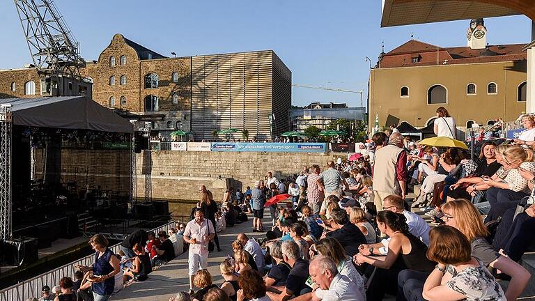 Am Hafen hat der Sommer begonnen       -  Jetzt hat auch am Alten Hafen der Sommer richtig begonnen &ndash; der musikalische. Am Freitagabend eröffnen das Philharmonische Orchester und Carolin auf der schwimmenden Bühne das diesjährige Musikfestival am Kulturspeicher.   Und die Treppen vor dem Heizkraftwerk waren dicht besetzt: 7000 Hafensommer-Freunde hatten sich für die Gratiskarten der traditionellen Sparda-Bank Classic Night beworben, 1500 konnten beim Eröffnungskonzert dabei sein.   Der Hafensommer läuft bis zum 6. August &ndash; Musik 17 Abende lang! Neu ist die Hafentour an diesem Samstag, 22. Juli: Im gesamten Kulturquartier Alter Hafen ist fünf Stunden lang Programm geboten. Los geht es um 17 Uhr im Museum. Um 21.30 Uhr spielen zum Abschluss Red Manhole.  Foto: Thomas Obermeier