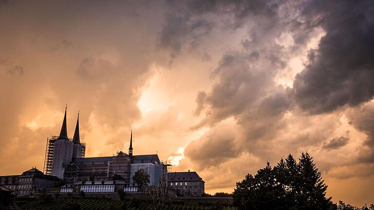 Gewitterwolken treffen auf den Sonnenuntergang, hier beobachtet über dem Kloster Michelsberg.