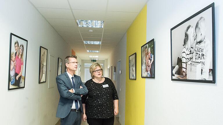 Vorsitzende Sandra Finzel zeigt Oberbürgermeister Sebastian Remelé die Fotoausstellung 'Glück kennt keine Behinderung', die der Verein 'Gemeinsam Leben – Gemeinsam Lernen' für die Informationsveranstaltung über die geplante inklusive Mittel- und Berufsschule nach Schweinfurt geholt hat.