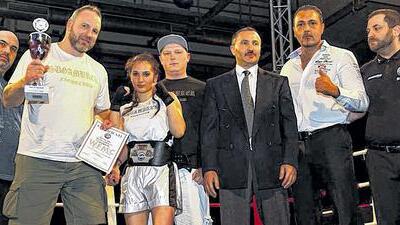 Kickboxerin Pinar Bolat triumphiert im Saarland - (pm) In der „Alten Grube“ von Großrosseln nahe Saarbrücken hat Kickboxerin Pinar Bolat bei der „Kampfnacht Fight for Saarland“ den „ProAm-Titel“ gewonnen. Die 15 Jahre alte Kampfsportlerin des Würzburger Sugambrer Fightclub e. V. setzte sich im K-1-Leichtkontakt-Wettbewerb bis 57 Kilogramm gegen die französische Titelverteidigerin Amandine Falck per technischem K. o. durch. Der Schützling von Trainer Frank Schneider bestimmte das Tempo, landete früh mit Faust und Fuß Treffer, sodass Falck bereits in der zweiten Runde angezählt werden musste. Bolat erhöhte den Druck und beherrschte den Kampf, den der Referee schließlich vorzeitig beendete. Unser Bild zeigt: (von links) Vater Selim Bolat, Trainer Frank Schneider, Pinar Bolat, Sekundant Andre Felde, WMF-Präsident Isa Akkus sowie die beiden Referees. Kickboxerin Pinar Bolat triumphiert im Saarland - (pm) In der „Alten Grube“ von Großrosseln nahe Saarbrücken hat Kickboxerin Pinar Bolat bei der „Kampfnacht Fight for Saarland“ den „ProAm-Titel“ gewonnen. Die 15 Jahre alte Kampfsportlerin des Würzburger Sugambrer Fightclub e. V. setzte sich im K-1-Leichtkontakt-Wettbewerb bis 57 Kilogramm gegen die französische Titelverteidigerin Amandine Falck per technischem K. o. durch. Der Schützling von Trainer Frank Schneider bestimmte das Tempo, landete früh mit Faust und Fuß Treffer, sodass Falck bereits in der zweiten Runde angezählt werden musste. Bolat erhöhte den Druck und beherrschte den Kampf, den der Referee schließlich vorzeitig beendete. Unser Bild zeigt: (von links) Vater Selim Bolat, Trainer Frank Schneider, Pinar Bolat, Sekundant Andre Felde, WMF-Präsident Isa Akkus sowie die beiden Referees.
