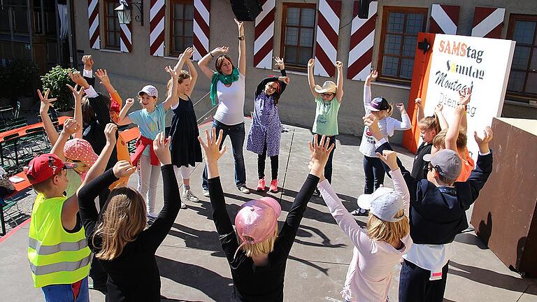 Beine ausschütteln, sich abklopfen und und strecken: Vor der Probe im Burghof kommen die Kinder der Grundschule Röttingen zum Warm-Up mit Frederike Faust (hinten, Mitte) zusammen.