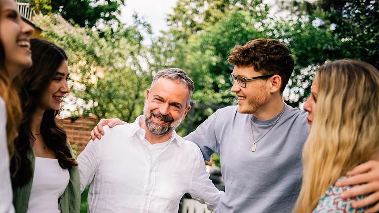 Eine Familie hält sich lachend in der Armen       -  Gemeinsam lachen: Humor sorgt für mehr Nähe in zwischenmenschlichen Beziehungen.