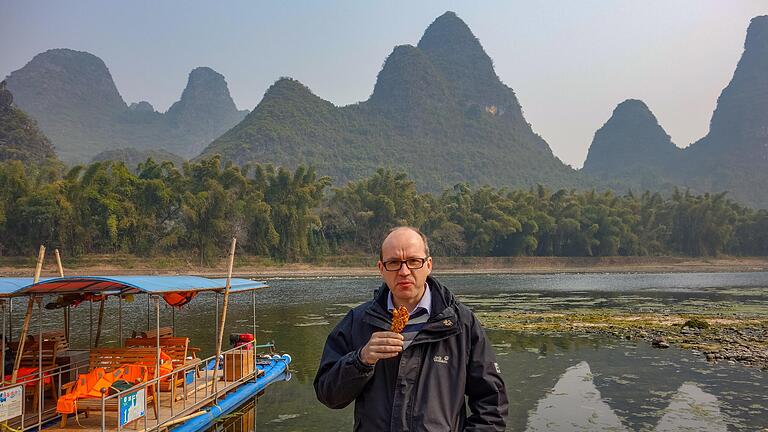 Während seiner Anstellung als Deutschlehrer in Wuhan hat Achim Höfling alle 34 Provinzen von China bereist. Unser Bild zeigt ihn in der Provinz Yangshou vor den Karstbergen Guangxi am Li-Fluss mit einem frisch gebackenen Kürbiskeks am Stil.&nbsp;