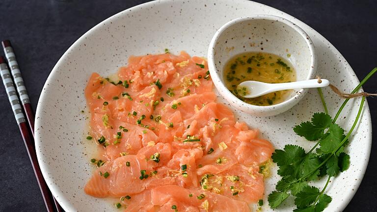 Lachs-Carpaccio mit asiatischem Dressing       -  Wenn man das Lachs-Carpaccio mit dem asiatischen Dressing beträufelt, wird die Farbe des Fischs etwas heller.