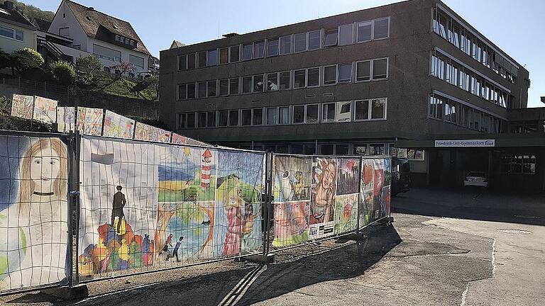 Die &bdquo;East-Side-Gallery&ldquo; des Friedrich-List-Gymnasiums in Gemünden: Die Banner zeigen Kunstwerke von Schülern quer durch alle Jahrgangsstufen, die in den beiden vergangenen Jahren entstanden. Etliche der Zeichnungen und Gemälde wurden bei Wettbewerben preisgekrönt. Andere greifen berühmte Vorbilder von Michelangelo über Jan Vermeer und Caspar David Friedrich bis zu Rene Magritte auf und interpretieren sie neu. Auch Malerei im Stil der australischen Ureinwohner ist zu sehen. Einige Arbeiten stammen auch aus Fotoseminaren. Die Banner mit den Kunstwerken kaschieren die Baugrube vor dem Eingang zur Schule, die vom Abriss der alten Turnhalle der Realschule zeugt und im Lauf der Sanierung des Gymnasiums wieder geschlossen wird. Den Druck der Kunstwerke auf die Banner hat der Schulverein ermöglicht.